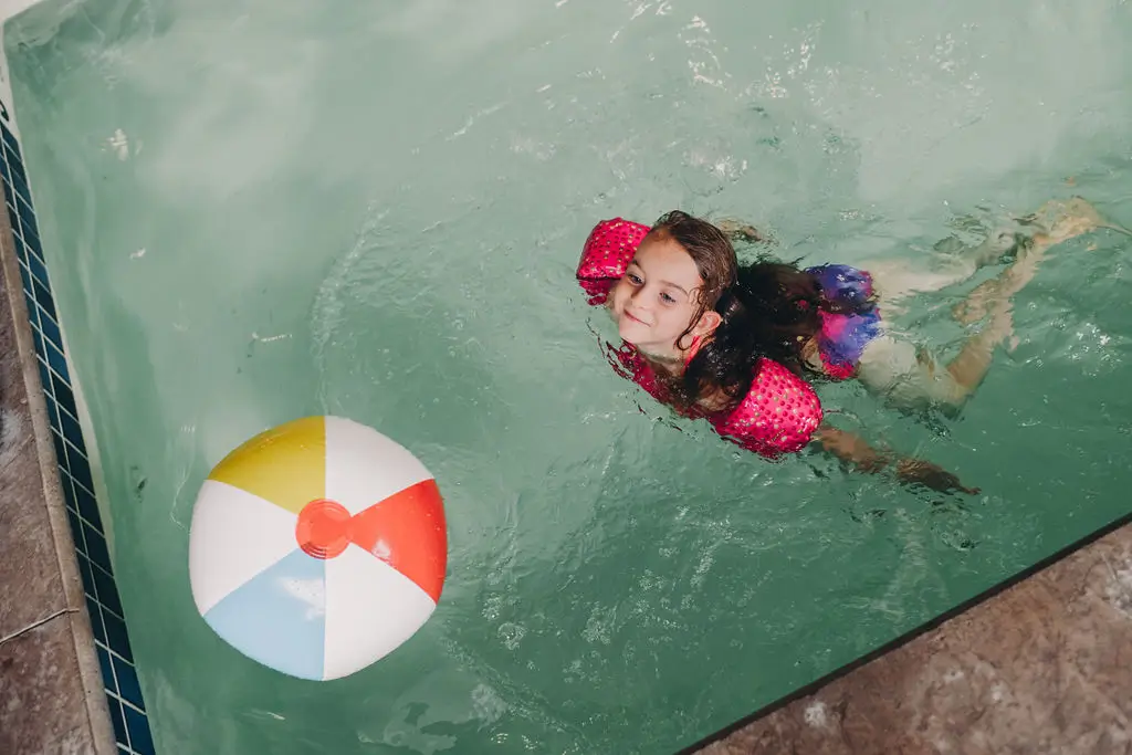 girl swimming towards beach ball